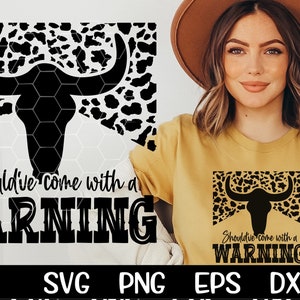 May include: A black and white cow skull graphic with a leopard print background. The text "Should've come with a WARNING" is below the skull. The graphic is on a white background.