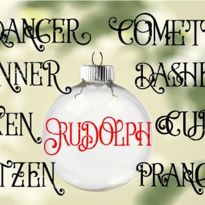 May include: A clear glass Christmas ornament with the names of Santa's reindeer written in black script around the ornament. The word "Rudolph" is written in red script in the center of the ornament.