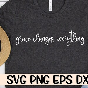 May include: A dark grey t-shirt with the text "grace changes everything" in white lettering. The shirt is lying flat on a white surface.