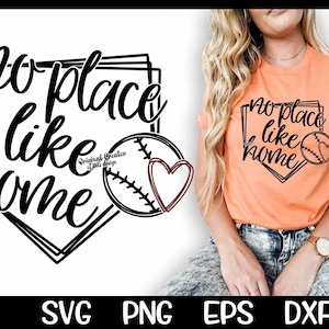 May include: A black and white graphic design of a baseball diamond with the text "no place like home" inside. A baseball with a red heart is in the center of the diamond. A woman is wearing a peach colored t-shirt with the same design printed on it.