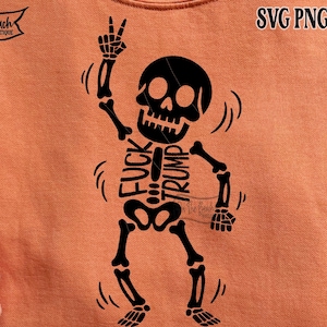Op de afbeelding: Oranje sweatshirt met een zwart skeletontwerp. Het skelet maakt een vredesteken en heeft de woorden "FUCK TRUMP" op zijn ribbenkast gedrukt. Het sweatshirt heeft ook de tekst "SVG PNG EPS DXF".