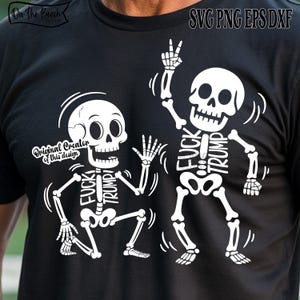 May include: Black t-shirt featuring a white graphic of two skeletons. One skeleton is giving a peace sign, and the other is waving. The words "FUCK TRUMP" are written on the skeletons' rib cages. The shirt also has the text "Original Creator of this design".