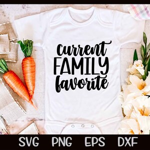 May include: White baby onesie with black text that reads "current family favourite". The onesie is surrounded by carrots and white flowers.