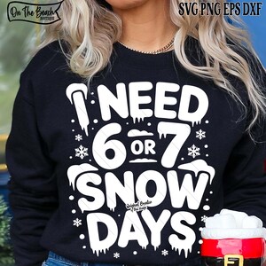 May include: Black sweatshirt with the text "I NEED 6 OR 7 SNOW DAYS" in white. The design includes snowflakes and icicles. The sweatshirt has the "On The Beach Boutique" logo in the upper left corner.