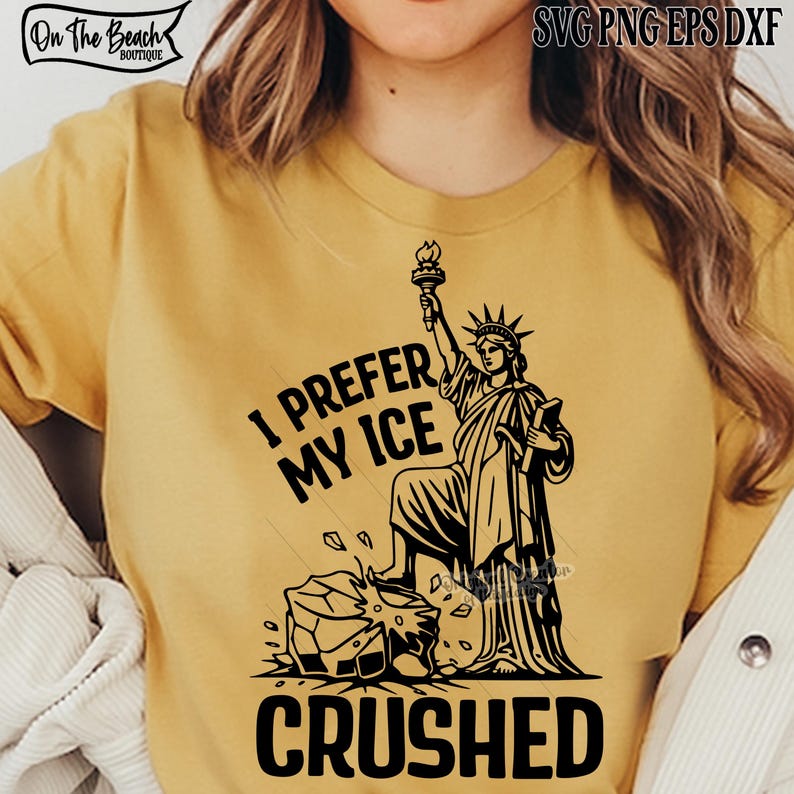 May include: Mustard yellow t-shirt with a black graphic of the Statue of Liberty holding a torch, standing on a block of ice. The text "I PREFER MY ICE CRUSHED" is printed below the graphic.