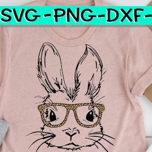 May include: A black and white line drawing of a bunny wearing leopard print glasses. The bunny is on a pink t-shirt.