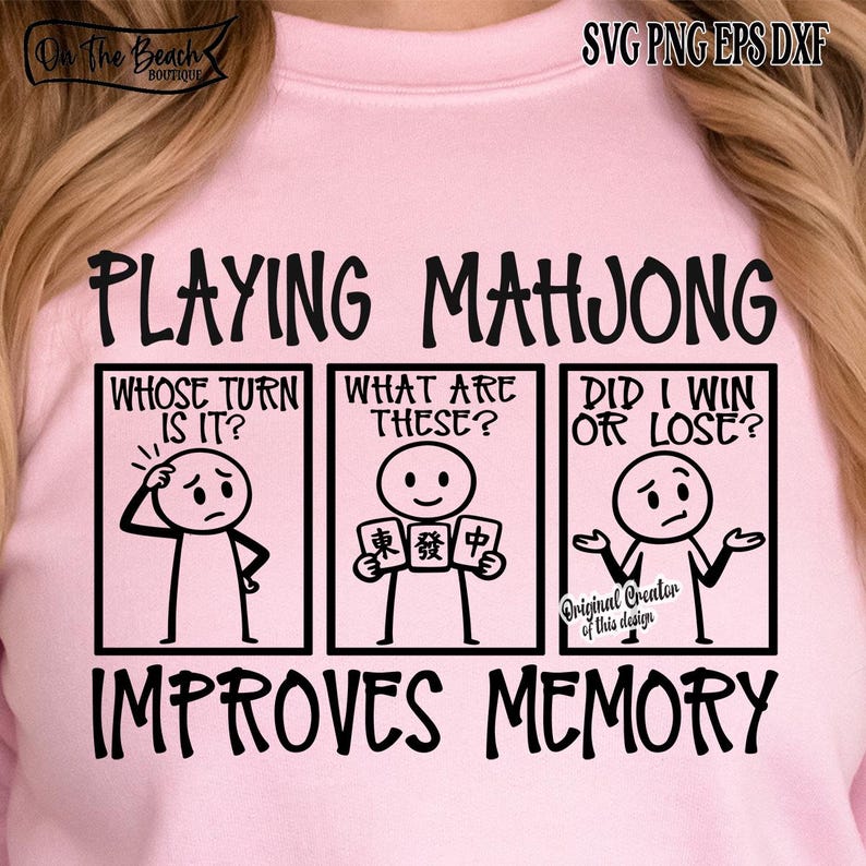 May include: Pink sweatshirt with a black graphic design. The design features the text "PLAYING MAHJONG IMPROVES MEMORY" with stick figures and questions about the game. The top left corner has the text "On The Beach Boutique".