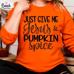 May include: Orange sweatshirt with the text "Just Give Me Jesus & Pumpkin Spice" in black lettering.