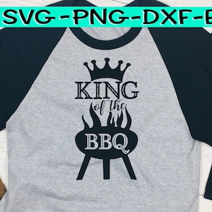 Könnte beinhalten: Ein grau-schwarzes Baseball-Shirt mit dem Text "King of the BBQ" und einer Krone über einem Grill mit Flammen.
