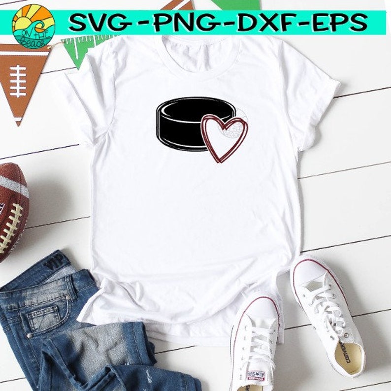 K&ouml;nnte beinhalten: Wei&szlig;es T-Shirt mit einem schwarzen Hockeypuck und einer roten Herzgrafik. Das Herz ist schwarz umrandet und rot gef&uuml;llt.