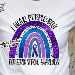 May include: A white t-shirt with a purple and blue glitter rainbow design. The rainbow has a blue ribbon in the center. The text "I wear purple & blue" is above the rainbow and the text "Pediatric Stroke Awareness" is below the rainbow.