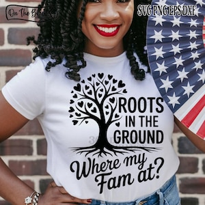 May include: White t-shirt with a black tree graphic and the text "ROOTS IN THE GROUND Where my Fam at?". The tree has heart-shaped leaves. The image also includes a fan with a stars and stripes design.
