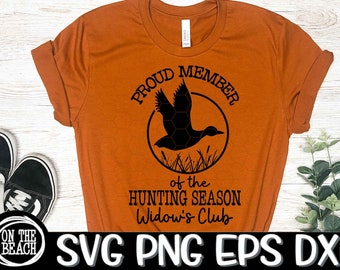 Pode incluir: Camiseta laranja com uma silhueta preta de um pato voando em um círculo com o texto "Proud Member of the Hunting Season Widow's Club".