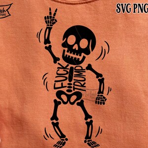 Op de afbeelding: Oranje sweatshirt met een zwart skeletontwerp. Het skelet maakt een vredesteken en heeft de woorden "FUCK TRUMP" op zijn ribbenkast gedrukt. Het sweatshirt heeft ook de tekst "SVG PNG EPS DXF".