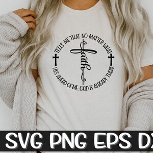 以下が含まれることがあります： 黒い円形のデザインに十字架と「Faith」の文字が入った、クリーム色のTシャツ。「どんなことがあっても、神はすでにそこにいる」というテキストが十字架の周りに書かれています。