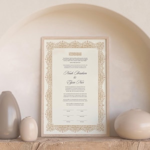 May include: A rectangular framed wedding certificate featuring a cream-colored background with black printed text and a decorative gold-toned filigree border. The names Noah Ibrahim and Elyza Nur are printed in a prominent script font in the center.