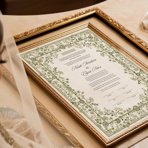May include: A framed document with a green floral border. The document is a Ketubah, a Jewish marriage contract, and includes the names "Noah Ibrahim" and "Elyza Noor".