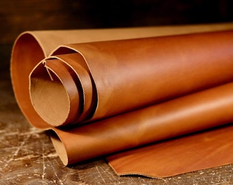 May include: Close-up of a roll of brown leather. The leather is rolled up and has a natural, rustic look.