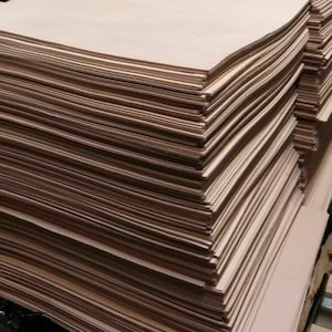 May include: A large stack of light brown leather sheets. The sheets are stacked neatly and are all the same size.