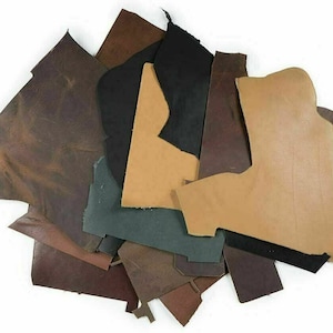 May include: Assortment of leather scraps in various shades of brown, tan, and black. The leather pieces are cut into different shapes and sizes, and some have a textured surface.