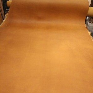 May include: A large roll of brown leather, unfurled and ready for use. The leather has a natural, rustic look and feel.