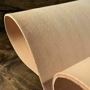 May include: Close-up of a light brown leather sheet rolled up. The leather has a natural, slightly rough texture.