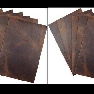 May include: A collection of rectangular, brown leather sheets with a distressed appearance. The sheets are arranged in a fan-like pattern, showcasing their texture and color variations. The leather has a rustic, aged look.