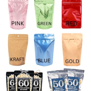 May include: A collection of stand-up pouches in pink, green, red, kraft, blue, gold, black, and silver. The black bags feature text reading 60 NEVER LOOKED SO GOOD! THANKS FOR POPPING BY. The silver bags feature text reading 50 AGED TO PERFECTION.