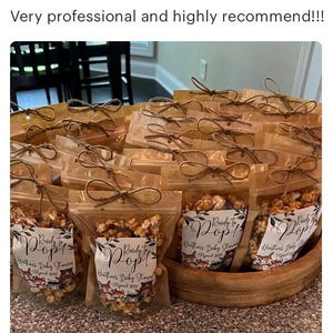 May include: A collection of clear plastic pouches filled with caramel popcorn, each tied with a brown twine bow at the top. The labels feature the text Ready to Pop! Heather's Baby Shower April 2024, decorated with illustrations of woodland animals.