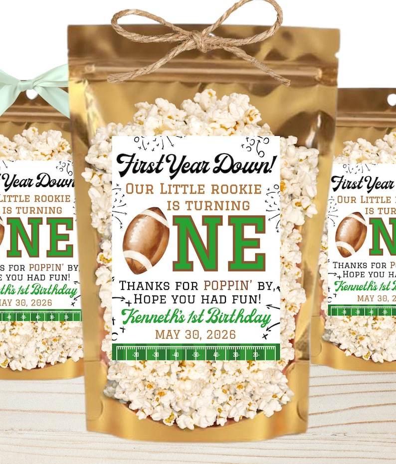 May include: A gold foil pouch filled with popcorn, featuring a label that reads First Year Down! Our Little Rookie Is Turning One. Thanks for Poppin' By, Hope You Had Fun! Kenneth's 1st Birthday May 30, 2026, with a football and field graphic.
