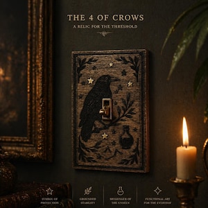 Könnte beinhalten: Dekorative Holz-Lichtschalterabdeckung mit einem geschnitzten Rabenmotiv, Sternen und botanischen Details. Die Abdeckung hat einen goldfarbenen Schalter und einen dunklen Holzrahmen. Text: "THE 4 OF CROWS" und "A RELIC FOR THE THRESHOLD".