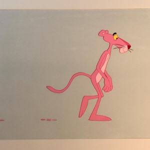 May include: A framed animation cel featuring the Pink Panther, a slender pink feline character with a light pink chest and yellow eyes, walking across a solid light blue background with small pink dash marks on the floor in front of the character.