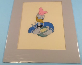 Può includere: Un'illustrazione di cartone animato di Paperino che indossa un cappello da cuoco rosa e una camicia blu con strisce bianche. Sta tenendo una ciotola e un paio di utensili, come se stesse preparando del cibo.