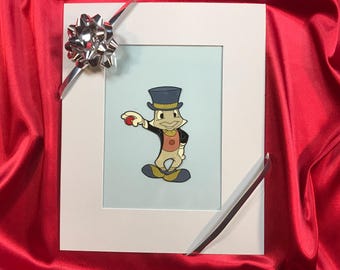 Può includere: Un'illustrazione incorniciata di un personaggio dei cartoni animati che indossa un cappello a cilindro e tiene una palla rossa. Il personaggio è in piedi su uno sfondo blu chiaro.