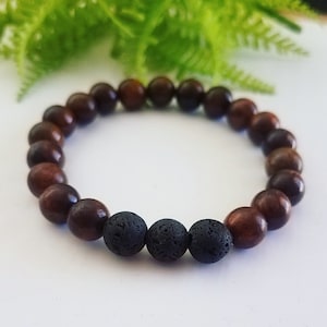 May include: A brown wooden beaded bracelet with three black lava rock beads.