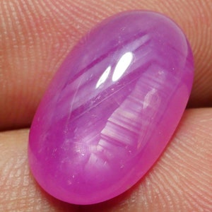 May include: A pink oval-shaped star sapphire gemstone with a white star effect.