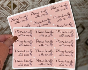 May include: A sheet of pink stickers with the text "Please handle with care" repeated 12 times. Each sticker has a small heart design.