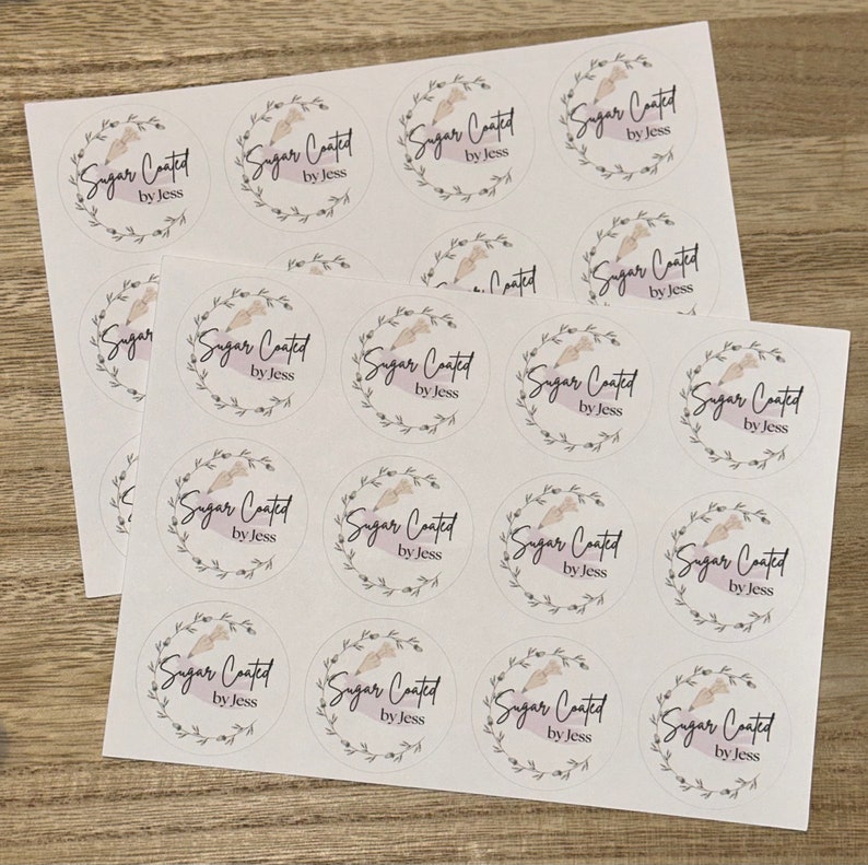 May include: A sheet of white paper with 16 round stickers. Each sticker has a floral wreath design with the text "Sugar Coated by Jess" in black.