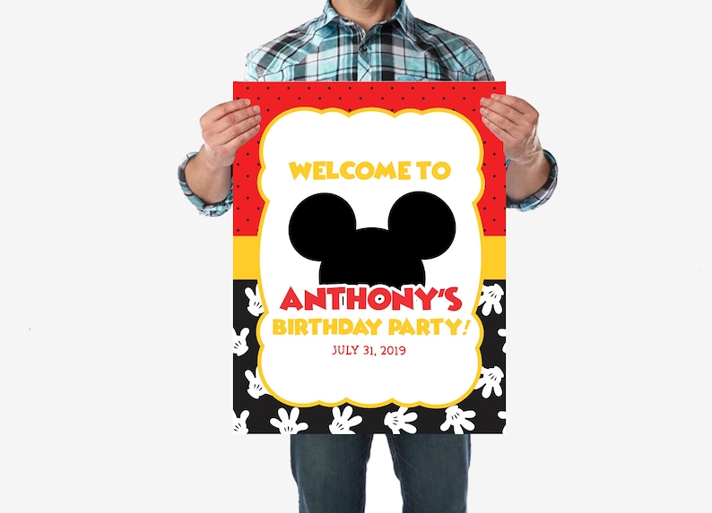 May include: A red, yellow, and black welcome sign with white polka dots. The sign features a black silhouette of Mickey Mouse's head and the text "Welcome to Anthony's Birthday Party! July 31, 2019".