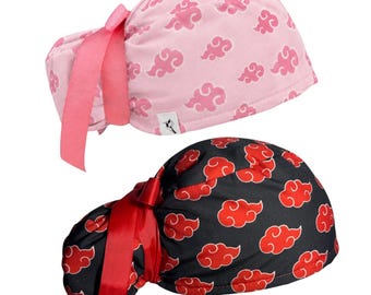 May include: Two scrub caps featuring a repeating cloud pattern. One cap is light pink with darker pink clouds and a pink ribbon tie. The other cap is black with red clouds and a red ribbon tie. Both caps have a gathered back and a small white label.