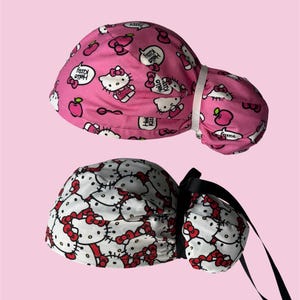 Puede incluir: Dos gorros quirúrgicos, uno rosa y otro blanco, con un patrón repetido de Hello Kitty. El gorro rosa tiene una banda elástica blanca. El gorro blanco tiene cintas negras. Ambos gorros presentan el personaje de Hello Kitty y bocadillos.
