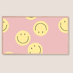 Könnte beinhalten: Ein gerahmter Druck mit einem sich wiederholenden Muster aus gelben Smiley-Gesichtern auf rosa Hintergrund. Die Smiley-Gesichter haben schwarze Umrisse und sind in verschiedenen Ausrichtungen. Der Rahmen ist hellholzfarben.