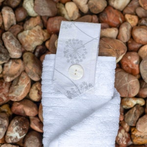 White hanging hand towel.  Full hand towel with white cotton tab attached with a white button. As Fancy As