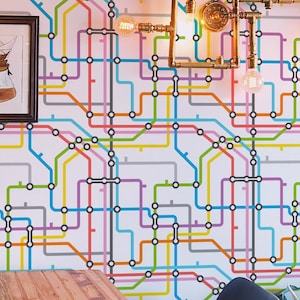 May include: A cafe interior featuring a table, chairs, and a wall with a colorful subway map design. A black pendant light hangs above the table. A framed picture and decorative lighting fixtures are also visible.