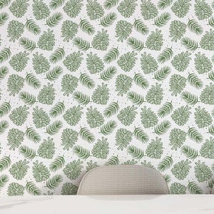 May include: A dining room scene featuring a white oval table with gold legs and four cream-colored chairs. The wallpaper has a repeating pattern of green leaves on a white background. A large, white, flower-shaped light fixture hangs above the table.