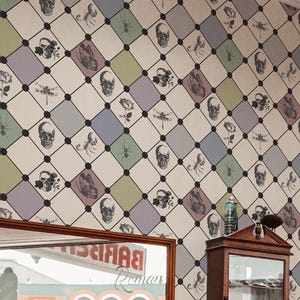 Peut inclure: Intérieur d'un salon de coiffure avec un homme près d'un fauteuil de barbier. Le magasin présente un sol à carreaux, un grand miroir et du papier peint avec des crânes et d'autres motifs. Le fauteuil de barbier est rouge.