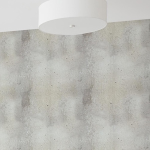 May include: A home office with a white desk and a black office chair. The desk is next to a white bookshelf filled with books. The wall is covered in a gray concrete-look wallpaper.