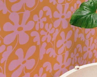 May include: A person relaxes in a white bathtub filled with pink flower petals. The bathtub is surrounded by lit candles and the background features a floral wallpaper.