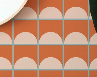 May include: A mid-century modern style wallpaper with a repeating pattern of orange squares and half-circle shapes in light pink. The design is framed by light blue lines. A wooden cabinet and mirror are in the foreground.
