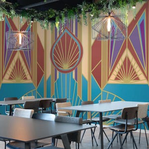 Puede incluir: Vista interior de un comedor moderno con mesas y sillas. Las paredes presentan un mural geométrico colorido en tonos azules, dorados, rojos y morados. Luces decorativas y vegetación cuelgan del techo.